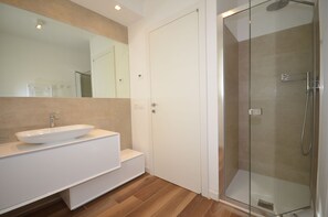 Ein modernes Badezimmer mit einem großen Spiegel, einem weißen Waschbecken und einer Duschkabine.