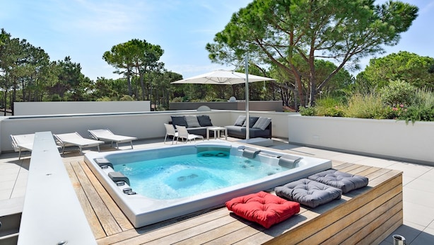 A rooftop pool area with a hot tub, lounge chairs, and a seating area with cushions. - Ville Summer (Lignano Sabbiadoro)