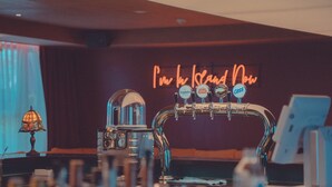 A bar area with a neon sign reading "I'm in the land now" and beer taps labeled with various brands. - Island.F Jeju (Seogwipo)