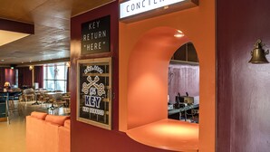 A hotel lobby with a 'Key Return Here' sign, a concierge desk, and a seating area with a curved wall. - Island.F Jeju (Seogwipo)