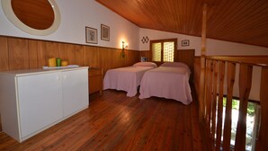 A room with wooden flooring, two beds with pink bedding, a white cabinet, and a wooden ceiling. - Villedda (Lignano Sabbiadoro)