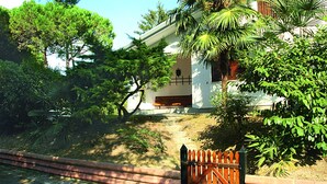A house with a white exterior, a wooden bench outside, and a metal gate. - Villedda (Lignano Sabbiadoro)