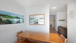 A dining area with a wooden table and chairs, a large mirror on the wall, and a clock. - Avalon 2- One of the best views that Yamba has to offer. (Yamba)