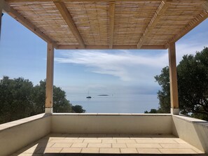 A covered outdoor area with a view of the sea and distant boats.