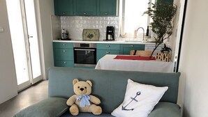 Un rincón acogedor con un sofá, un oso de peluche y una almohada con diseño de ancla.