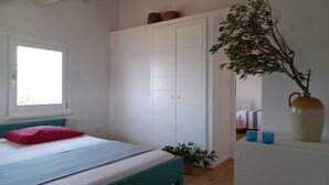 Un dormitorio con cama, armario, ventana y planta en maceta.
