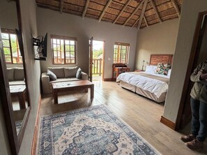 Een kamer met een bed, een bank, een bureau en een groot raam.