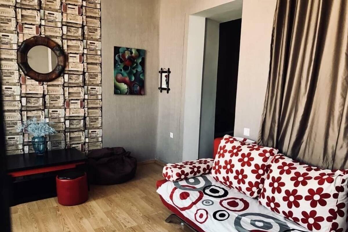 A room with a patterned sofa, a mirror, and a wall decorated with vintage-style boxes.