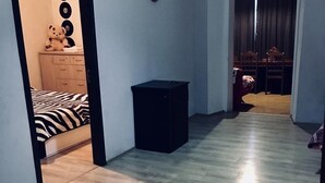 A hallway with a bed, a black cabinet, and a dining area with a table and chairs. - Apartment on Tsamebuli Ave (Tbilisi)