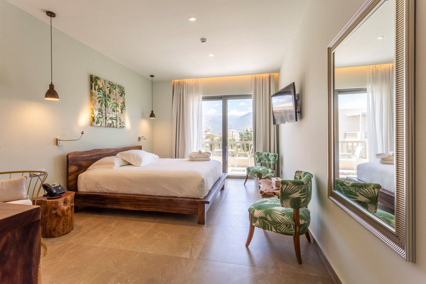 A hotel room with a bed, a desk, a chair, a TV, and a large window with a view.