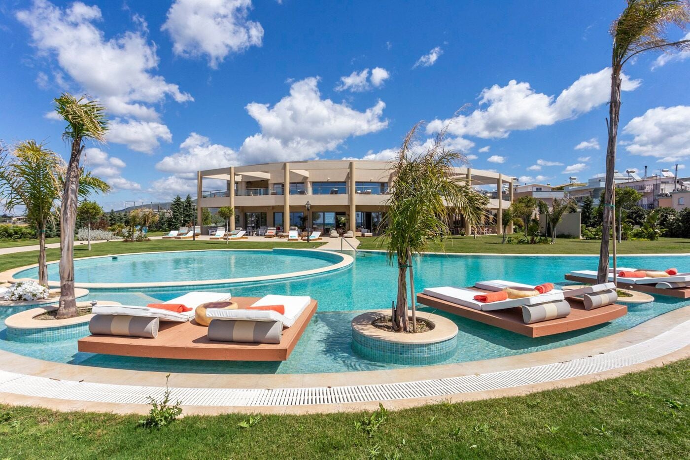 A pool area with lounge chairs and a modern building in the background.