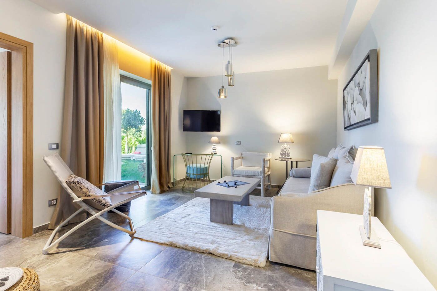 Una sala de estar moderna con un sofá, un sillón, una mesita de centro y un televisor montado en la pared.