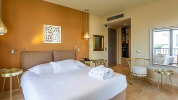 A hotel room with a large bed, a sitting area with a chair and a small table, a mirror, and a view of the outside balcony.