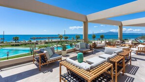Una terraza en la azotea con mobiliario exterior, piscina y vista al mar.