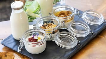 Una bandeja con diversos alimentos, incluyendo tarros de yogur y granola, sobre una mesa de madera.