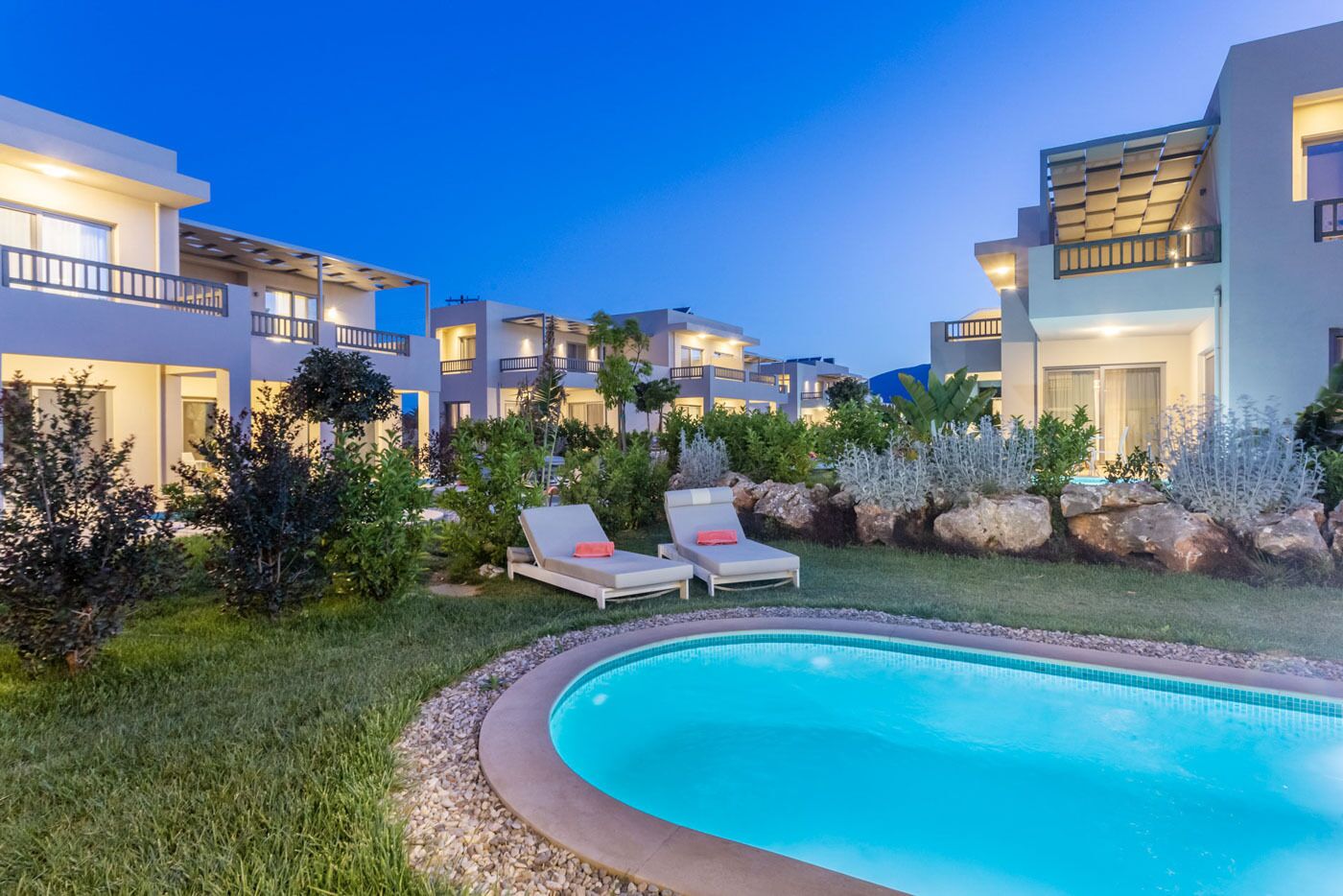 Un hôtel moderne doté d’une piscine, de chaises longues et de jardins bien entretenus.