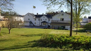 A large white building with a flag, a covered entrance, and a car parked in front. - Gamleby Hotell (Gamleby)