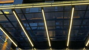 A modern building with a glass facade and illuminated horizontal lines.