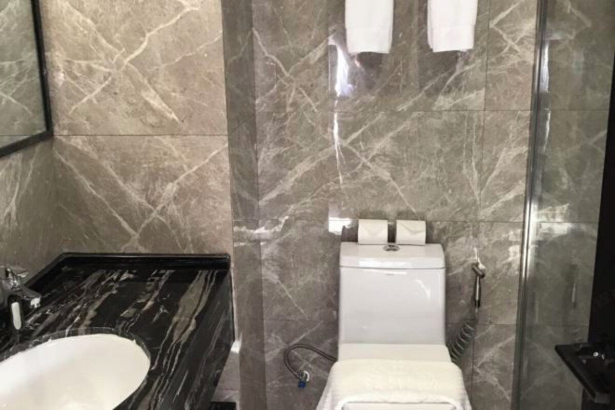 Un baño con lavamanos de mármol, inodoro y cabina de ducha con mampara de vidrio.