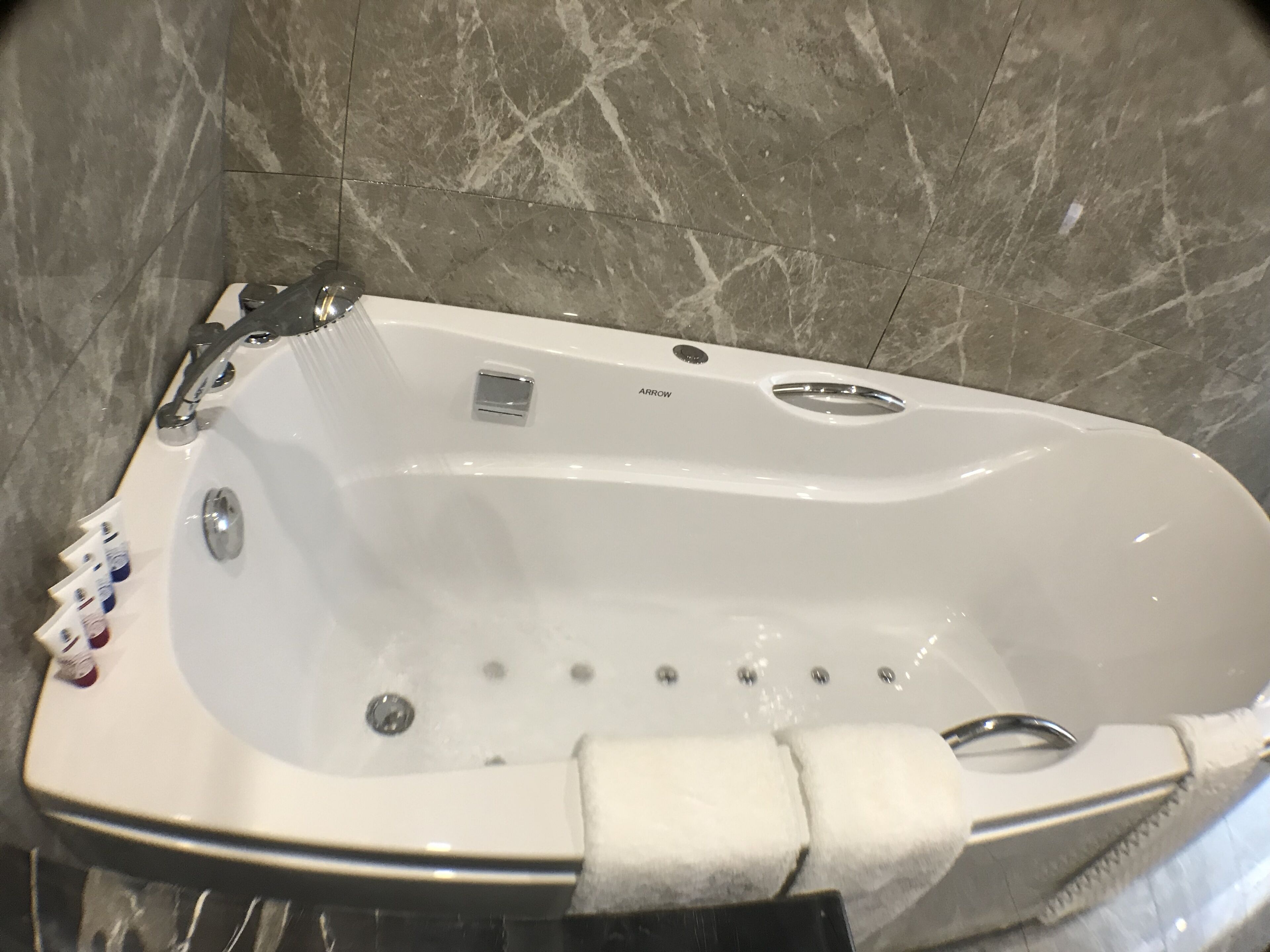 A white bathtub with a control panel, a small button, and a drain.