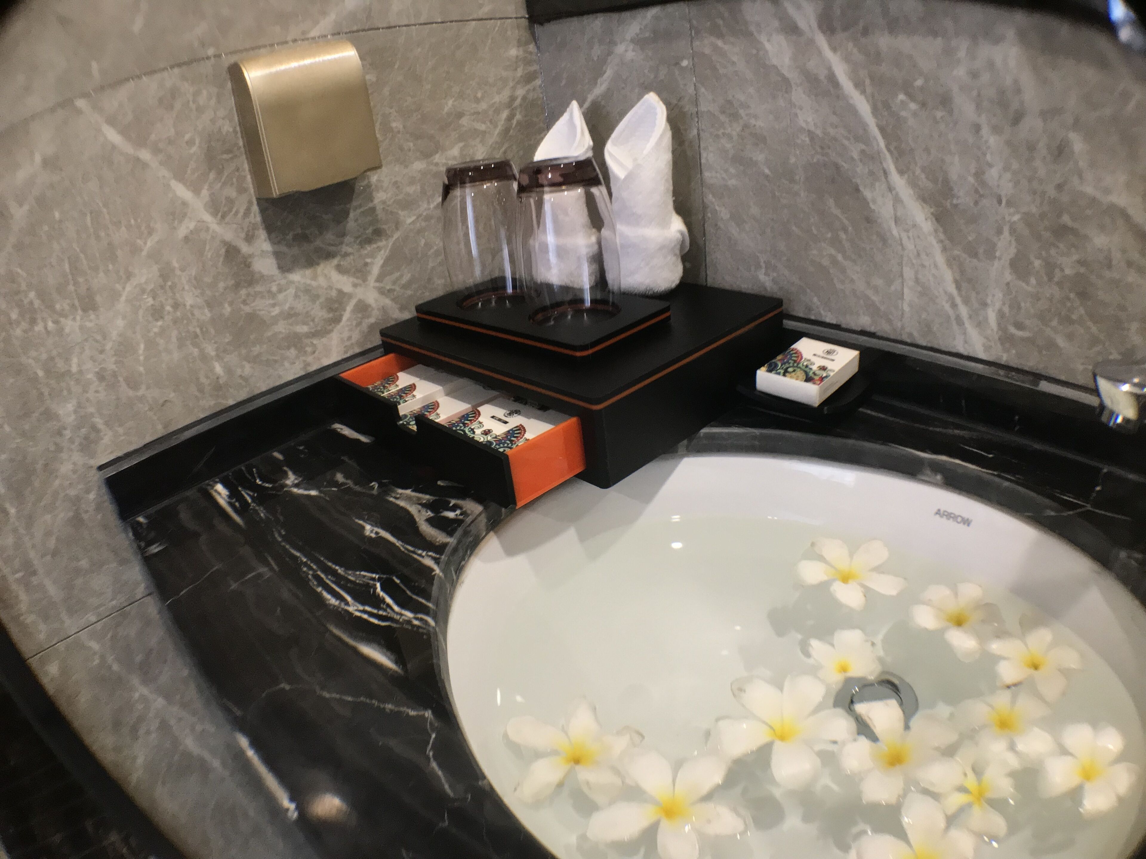 A bathroom with a marble sink, a towel rack, and a soap dispenser.