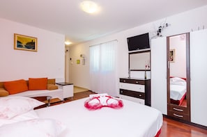 Relax in a stylish room with a large bed, sofa, desk, and wardrobe, featuring a television and a mirror.