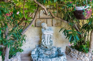 Surrounded by lush greenery, a serene stone sculpture sits atop a rock formation.