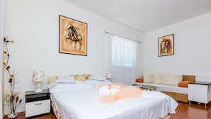 A bedroom with a large bed, a bedside table with a lamp, a sofa, and two framed pictures on the walls. - Apartments Aura - Comfort Studio Apartment f with shared swimming pool (Dubrovnik)