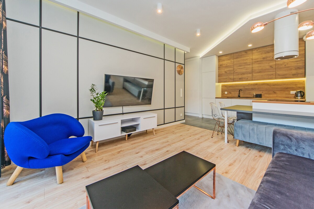 Een moderne woonkamer met een flatscreen televisie, een blauwe fauteuil, een salontafel en een bank.