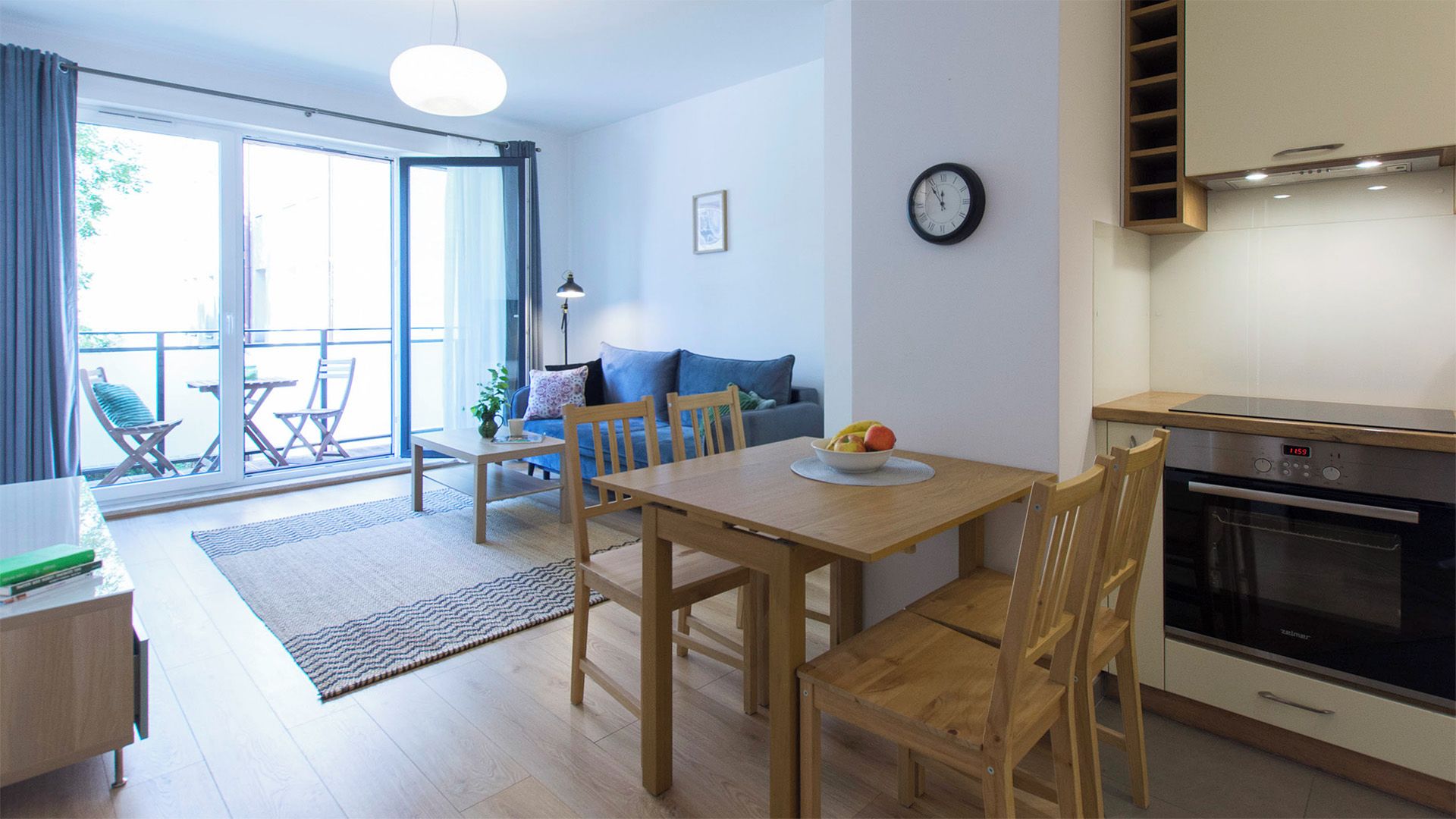 En moderne lejlighed med spiseområde, køkken og en balkon med udendørs møbler.