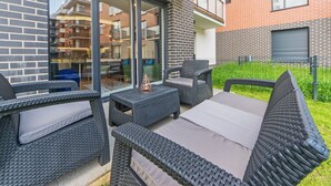 Un espace extérieur aménagé avec des meubles en osier et une porte vitrée donnant sur un balcon.