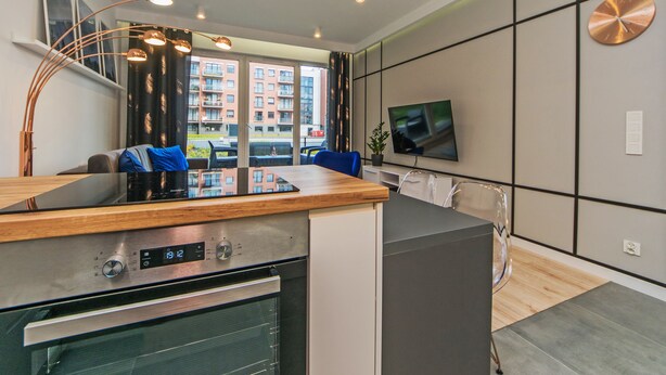 Una cocina moderna con horno empotrado, un comedor con mesa de madera y un amplio ventanal con vistas a la ciudad.