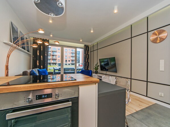 Een moderne keuken met een inbouwoven, een eethoek met een houten tafel, en een groot raam met uitzicht op de stad.