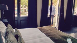 Un dormitorio con cama, mesita de noche y ventana con cortinas.