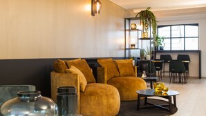 Una sala de estar moderna con un sofá, una mesa de centro y elementos decorativos. Se observa un comedor con sillas y una mesa al fondo.