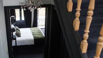 A bedroom with a bed, a chandelier, and a view through a window.
