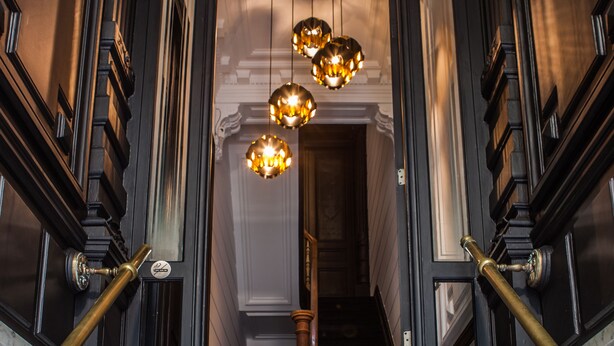 Una imponente escalera con barandales ornamentales y un candelabro con múltiples lámparas.