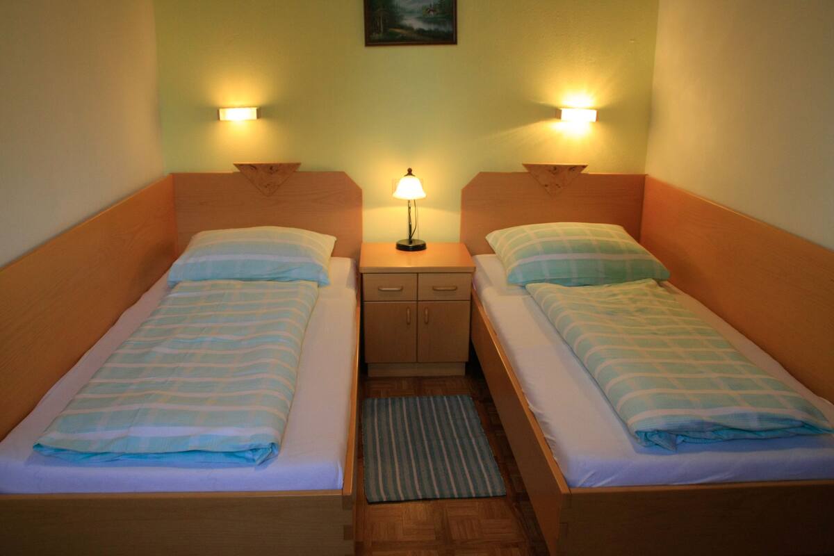 A twin room with two single beds, a nightstand with a lamp, and a small cabinet.