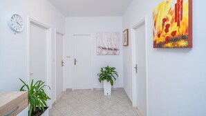 Ein Flur mit weißen Wänden, einer Uhr, einem Blumentopf und einem Gemälde.