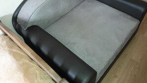 A sectional sofa with a grey and black color scheme, positioned against a wooden floor and a white wall. - Apartment on Lermontov Str. (Tbilisi)