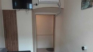 A hotel room with two single beds, a flat-screen TV mounted on the wall, an air conditioning unit, and a painting on the wall. - Apartment on Lermontov Str. (Tbilisi)