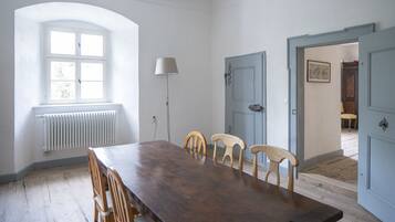 Ein Esszimmer mit Holztisch und -stühlen, einem Fenster mit Heizkörper und einer Lampe.