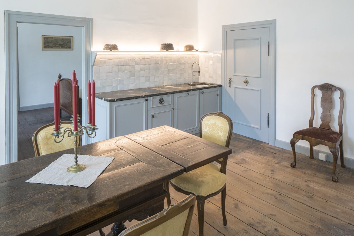 A dining area with a wooden table, chairs, a candelabra, and a tiled backsplash.