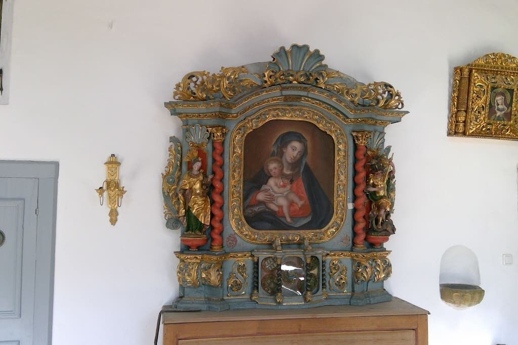 A religious icon with ornate gold and blue decorations, a wooden base, and a wall-mounted design.