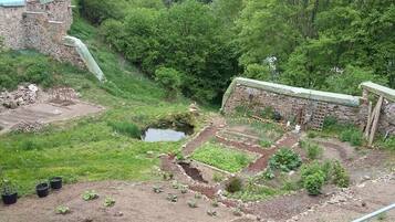 Ein Garten mit erhöhten Blumenbeeten, einem kleinen Teich und einer Steinmauer.
