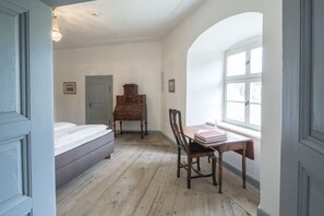 A room with a bed, a wooden chest, a desk with books, and a window. - Castle near Regensburg (Wenzenbach)