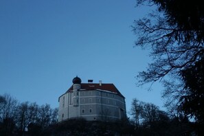 A large, historic building with a round tower and a red roof, surrounded by trees. - Castle near Regensburg (Wenzenbach)