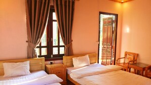 A room with two beds, a wooden nightstand, a chair, and a window with curtains. - Thanh Homestay (Sa Pa)
