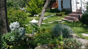 A white building with a garden in front, including a pathway and steps leading to the entrance.