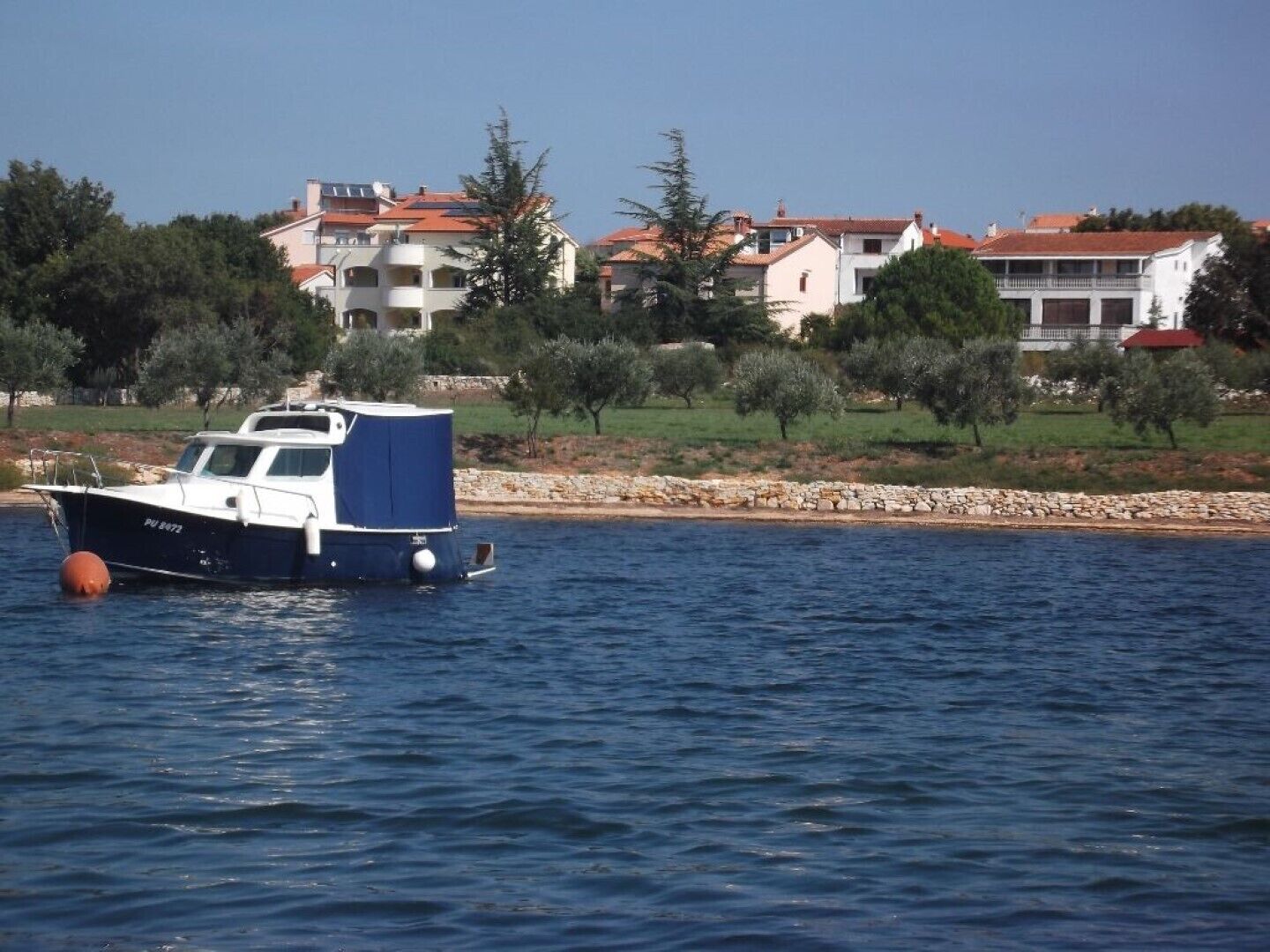 A boat with a blue cabin floating on calm water.